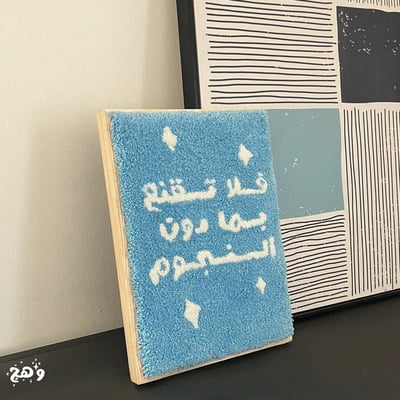 صورة لوحة جدارية بخيوط القطن وعبارة فلا تقنع بما دون النجوم