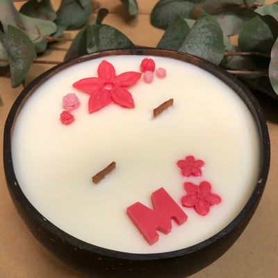 صورة شمعة معطرة بقالب جوز الهند الطبيعي مع امكانية اختيار اضافة حرف للزينة.